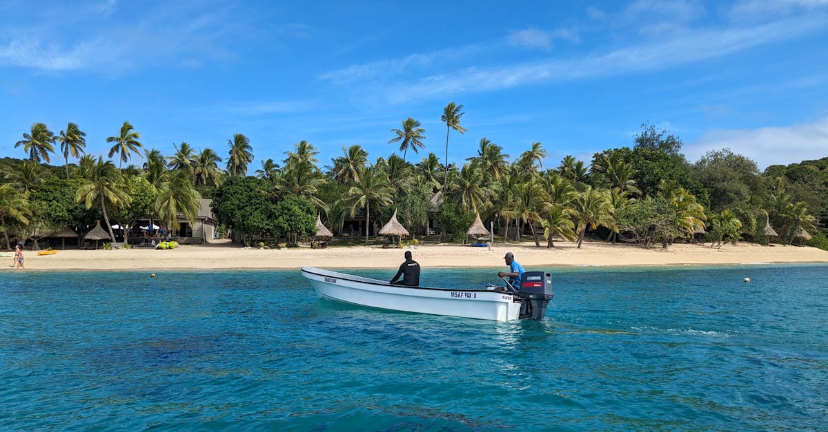 Explore a serene tropical island with palm trees and a boat on crystal clear waters.